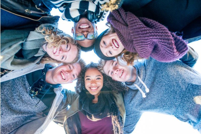 Ragazzi in cerchio guardano in basso in abiti invernali sorridendo