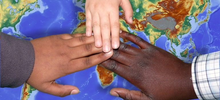 Immagine con tre mani che toccano il mondo