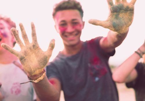 4 giovani ragazzi con i volti e le mani colorate che si divertono per la scuola estiva oltre la media