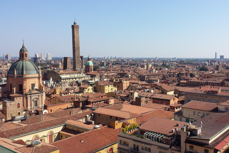 Vista panoramica di Bologna, con i suoi caratteristici tetti rossi e un cielo azzurro e terso.
