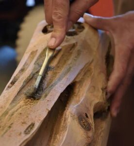 Due mani con un attrezzo lavorano del legno.