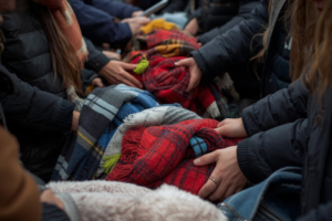 mani e braccia di persone che raccolgono coperte all'aperto con giubbotti per il piano freddo e allerte climatiche
